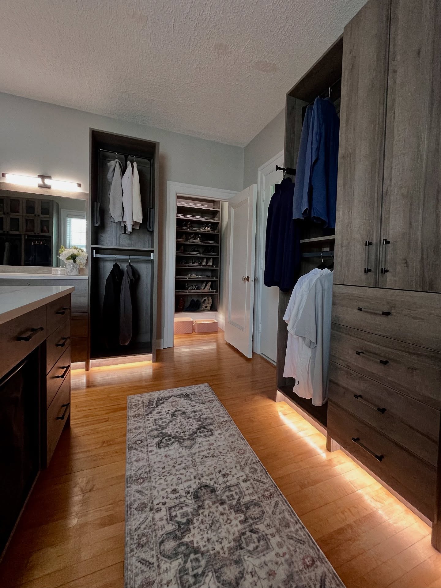 Winnipeg bedroom converted to a wardrobe room with tall wood-tone cabinets, hanging zones, and warm lighting