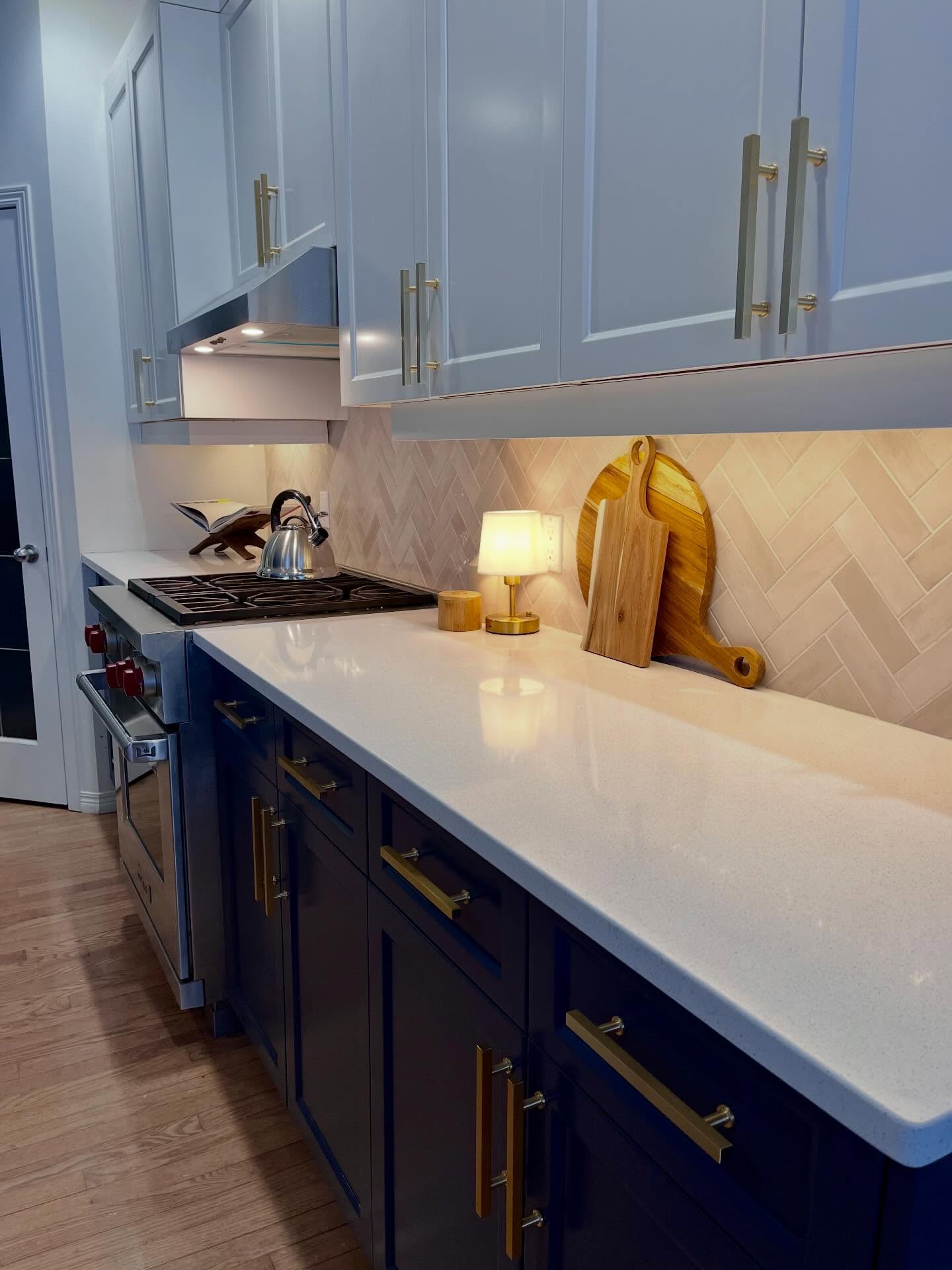 Project Lily counter run with cream herringbone tile, white quartz, navy bases, and brass pulls