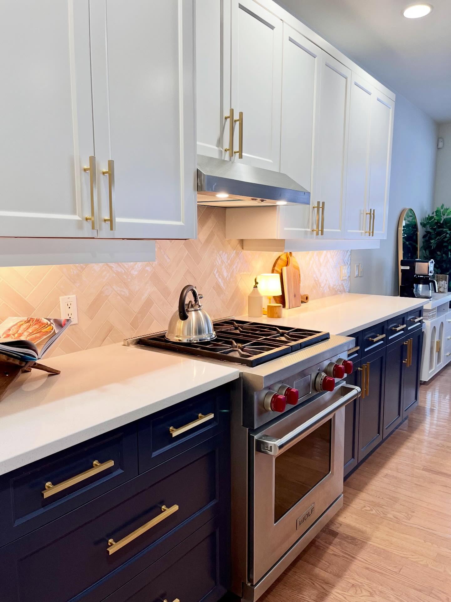 Finished Winnipeg kitchen with navy lower cabinets, cream herringbone tile, and a stainless gas range